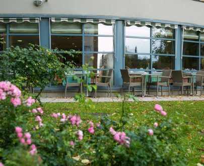 Le jardin d'Arcade de Fontenay avec tables, espace vert et terrasse.